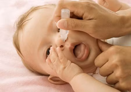 Nước muối. Nước muối là một phương thuốc phổ biến lại an toàn chữa nghẹt mũi cho bé. Bạn có thể mua thuốc nhỏ mũi dạng muối sinh lý hay dạng nước biển (dùng được cho các bé) hoặc bạn tự chuẩn bị nước muối nhỏ mũi cho con ngay tại nhà. Để làm nước muối nhỏ mũi cho con rất đơn giản, bạn chỉ cần pha một cốc nước ấm với một nửa thìa cafe muối ăn là được. Khi nhỏ giọt dung dịch nước muối vào lỗ mũi của bé cần lưu ý, chỉ một giọt cho mỗi lỗ mũi là đủ.