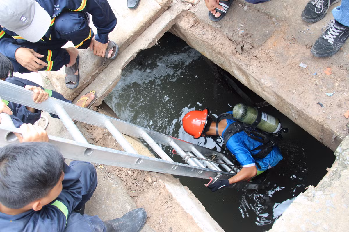 Tại hiện trường, do trận mưa chiều 6-9 rất lớn, nước ngập cao và chảy xối xả, bật tung một số nắp cống, khiến Tỷ bị rơi xuống dòng nước. Người nhái được huy động xuống cống để tìm kiếm nạn nhân. Ảnh: Bá Sơn