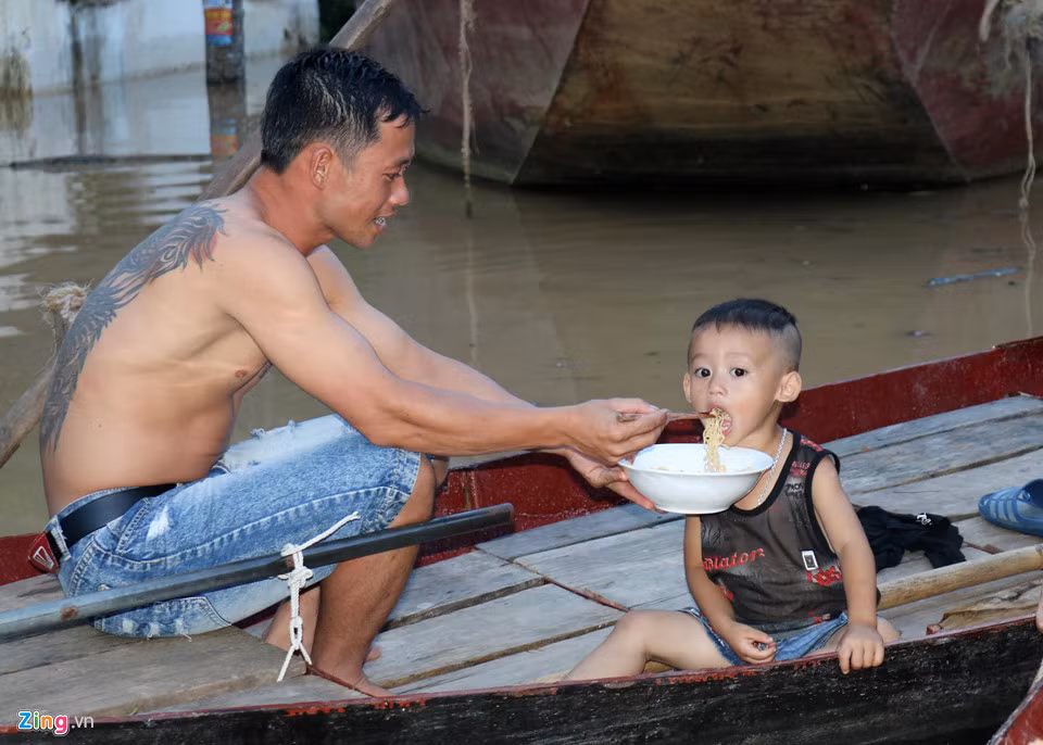 Với người dân vùng lũ, những ngày “sống trên nước” này, bữa ăn của cả nhà có thể chỉ là những bát mì tôm. Anh nguyễn Văn Lâm ở khối 1, thị trấn Đô Lương đang ngồi trên thuyền cho con ăn.