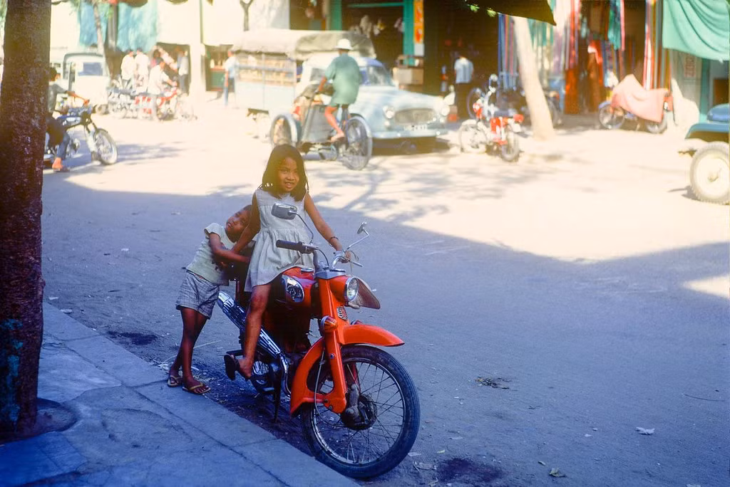 Hai em bé Nha Trang chơi đùa với chiếc xe Honda.