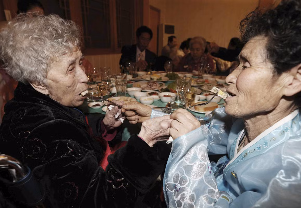 Trong ảnh, là cảnh mẹ con cụ bà Lee Young Shil (Hàn Quốc), 87 tuổi (trái) và người con gái Myung- sook, 66 tuổi đang sống ở Triều Tiên đút cho nhau ăn.