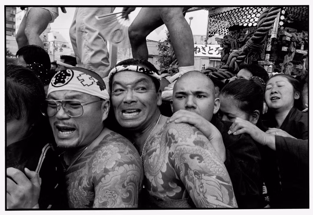 Các thành viên băng 23 khiêng chiếc kiệu Mikoshi truyền thống trong lễ hội Matsuri năm 1998. Khác với các băng đảng tội phạm quốc tế, Yakuza Nhật Bản có thể công khai tham gia vào các hoạt động xã hội. Ảnh: Bruce Gilden/ Magnum Photos.