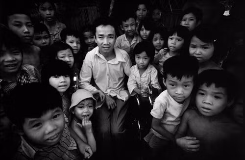 Trẻ em tụ tập quanh một người thương binh để nghe kể chuyện thời chiến tranh, 1980. Ảnh:Philip Jones Griffiths/ Magnum Photos.