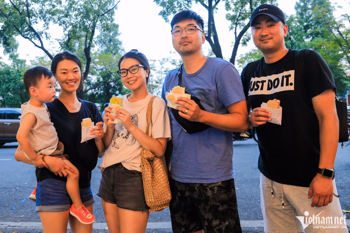 Chị Ánh và anh Sung (giữa, về Hà Nội từ Mỹ) sau một hồi loay hoay nhìn hai hàng kem kẹp Singapore gần nhau đã không biết chọn quán nào. Cuối cùng chị Ánh quyết định mua mỗi bên 2 chiếc. "Tôi thấy kem ở hai cửa hàng hương vị đều giống nhau, đều có mùi thơm của trái cây và không bị quá ngọt", người phụ nữ chia sẻ.