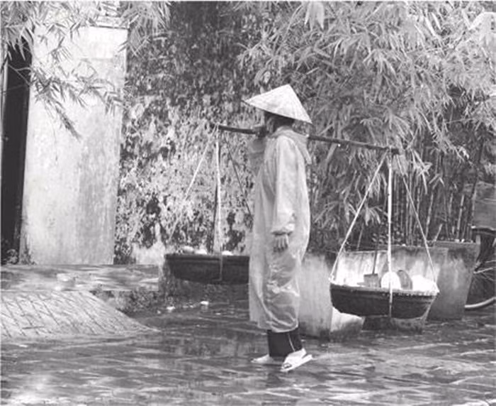 Bức ảnh người phụ nữ bán rong được chia sẻ kèm theo dòng thơ đầy cảm động: "Mưa rơi trên đường vội vã/ Dáng mẹ hao gầy tất tả đường trơn/ Chiếc áo nâu chỉ rách vai sờn/ Lưng mẹ còng nay trùng hơn một chút/ Đôi chân trần bao lần ngã hụt/ Dành tặng cho con giây phút yên bình". 
