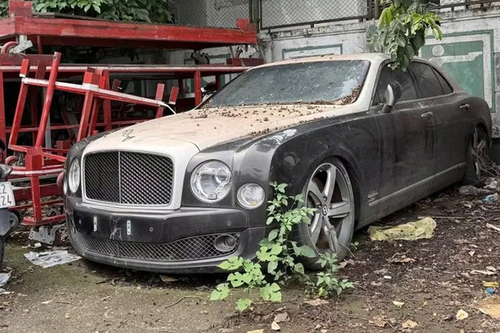 Nhìn vào ngoại thất chiếc xe Bentley Mulsanne bị "vứt xó" ở sân bóng Hà Nội này, này sẽ khiến không ít người tiếc vì xe bị hư hỏng 4 phuộc hơi, ngoại thất thì bám đầy bụi, nhiều khả năng xe đã đỗ ở đây nhiều tháng, có khi là tính bằng năm.