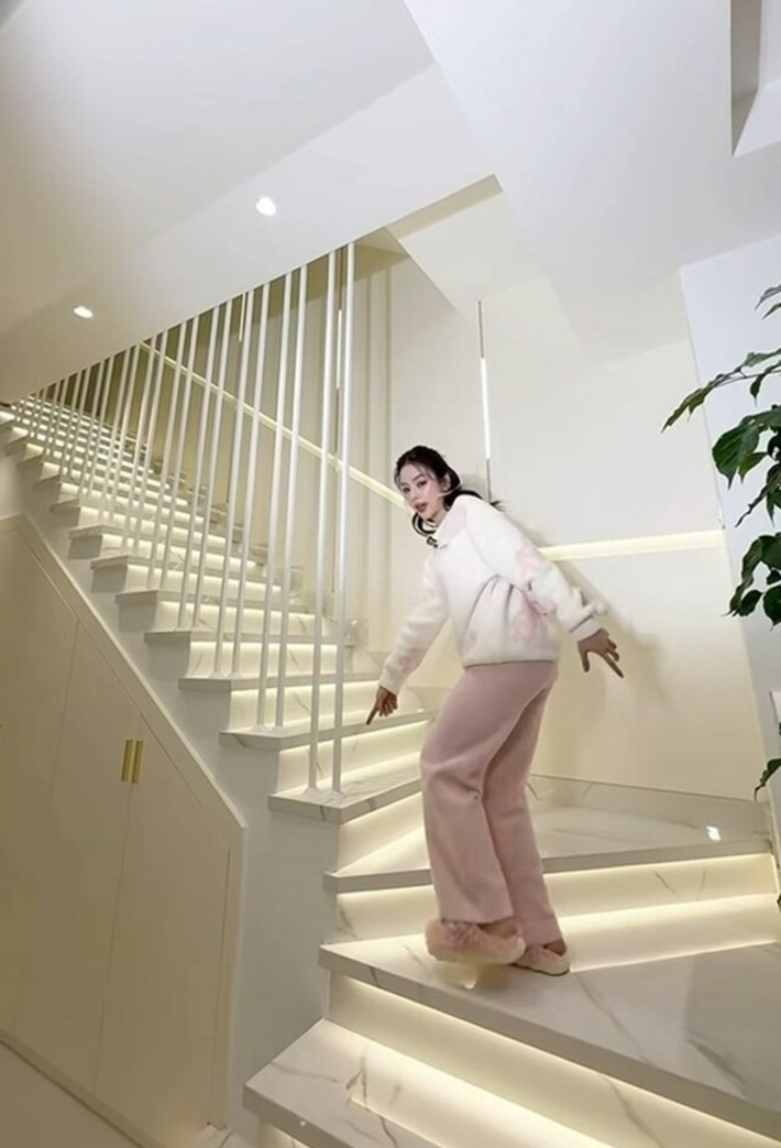 Bên trong biệt thự, DJ Mie vẫn chuộng style đơn giản với tone trắng chủ yếu. Không gian tầng 1 gồm phòng khách thông với phòng ăn và bếp. Phòng khách vô cùng rộng rãi, nổi bật với bộ sofa thiết kế tối giản nhưng sang trọng. Phần cầu thang cùng tone trắng với không gian bên trong biệt thự, được lắp hệ thống đèn phát sáng tự động mỗi khi lên xuống cầu thang để vừa sáng nhà, vừa thuận tiện trong sinh hoạt đời thường.
