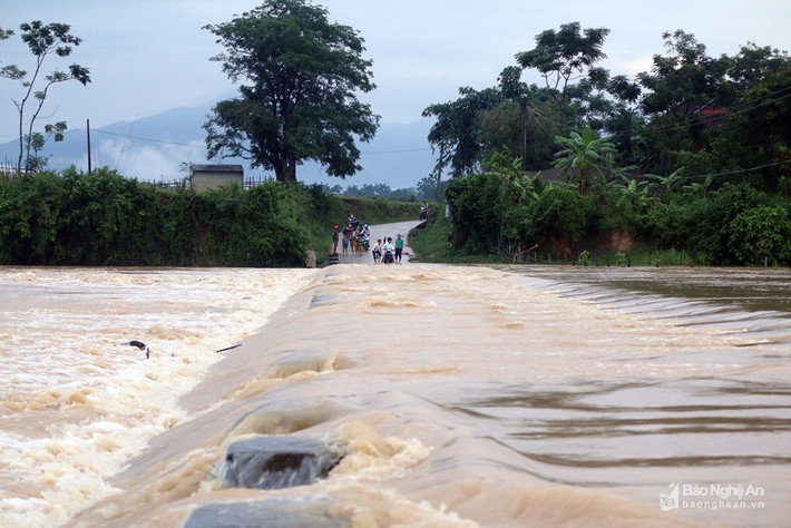 Khi cầu tràn bị ngập, người dân phải vòng qua xã Châu Bính với quãng đường dài thêm 3km để về nhà. Tuy nhiên, có nhiều người bất chấp nguy hiểm, liều mình vượt qua dòng lũ để về bản. Ảnh: Hữu Vi