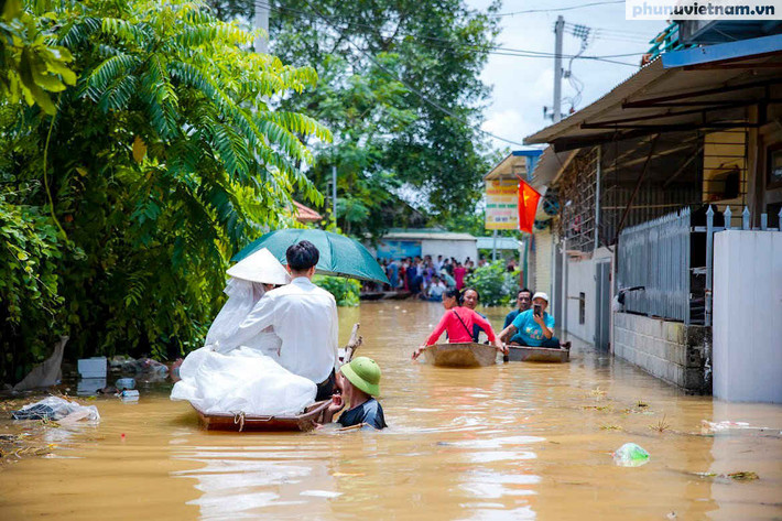 Chia sẻ về những bức ảnh cưới của mình, anh Luyện cho biết nước dâng ngập khu vực cánh đồng, đến chiều thì nước chơm chớm vào đường làng. Khu vực đường dựng rạp trước cửa nhà anh Luyện cao hơn, nên không bị ảnh hưởng nhiều. Đến tối, nước dâng cao hơn, phải thu dẹp từ sớm, gia đình mới chỉ làm được 80 mâm, trong khi dự kiến là 110 mâm. Ảnh: Phụ nữ Việt Nam