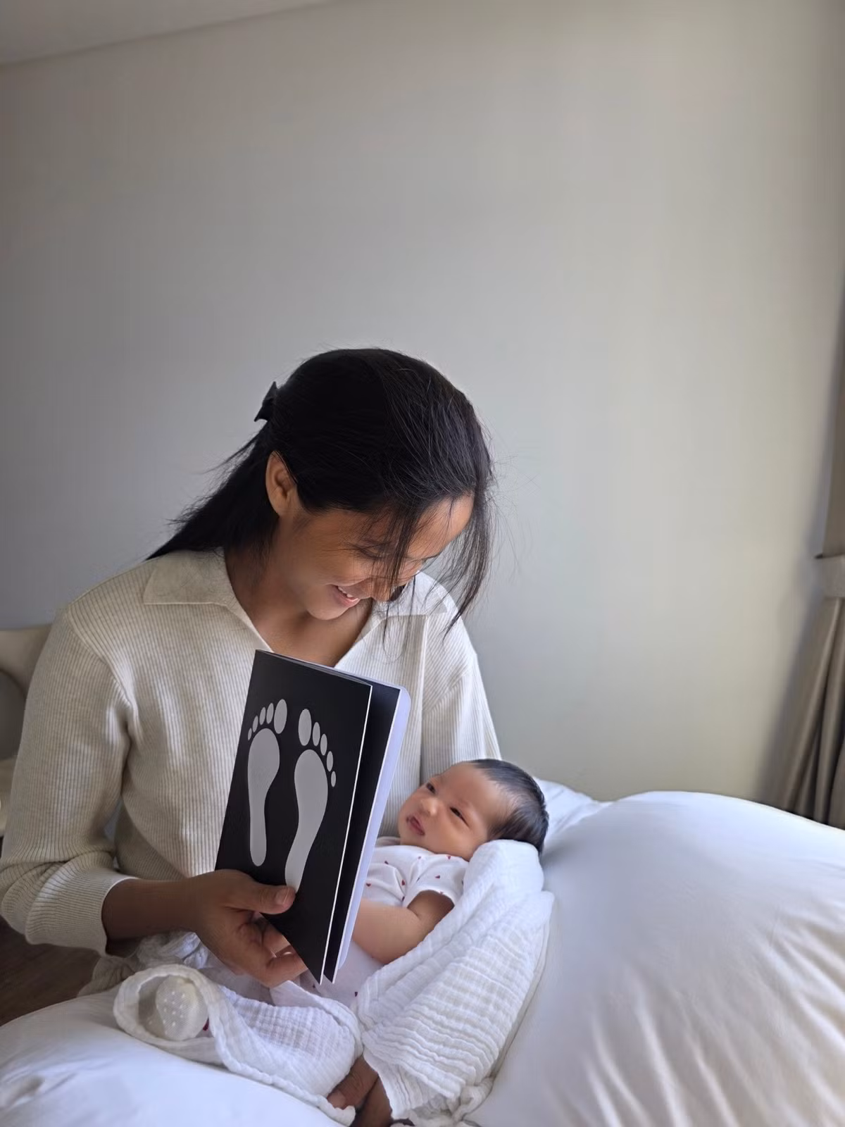 Hoa hậu H'Hen Niê cho con gái mới sinh xem tranh đen trắng. Ảnh: FB H'Hen Niê