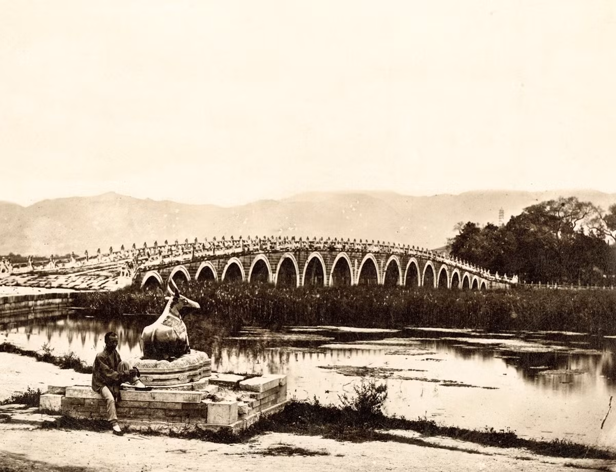 Một người đàn ông ngồi trước Thập Thất Khổng Kiều - cầu vòm lớn bắc qua hồ Côn Minh trong Di Hòa Viên.