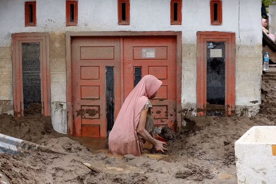Một phụ nữ dọn bùn khỏi ngôi nhà ở Meureudu, Pidie Jaya, Indonesia. Ảnh: EPA.