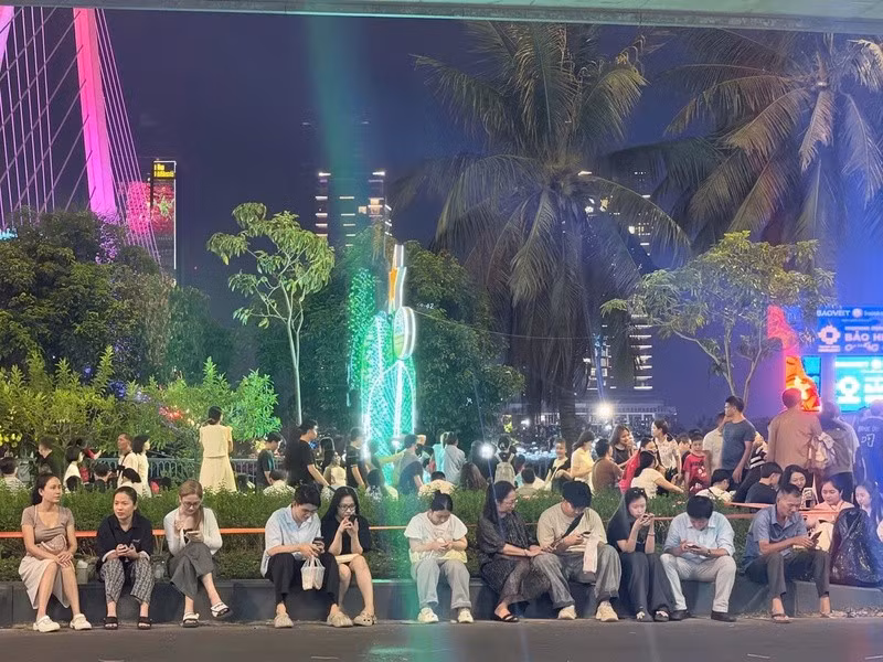 Nhiều bạn trẻ chọn vị trí đẹp tại khu vực bến Bạch Đằng để cùng bạn bè tận hưởng trọn vẹn màn pháo hoa rực rỡ. Ảnh: Minh Anh.