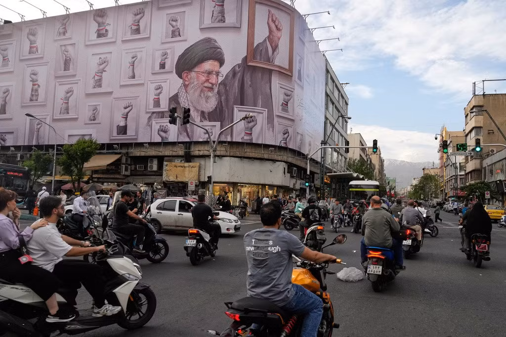 Cuộc sống của người dân ở thủ đô Tehran dường như vẫn diễn ra bình thường dù Mỹ và Iran chưa đạt được thỏa thuận hòa bình. Trong ảnh: Những chiếc xe máy chạy ngang qua một tòa nhà có hình ảnh cố Lãnh tụ tối cao Iran Ayatollah Ali Khamenei - người đã thiệt mạng trong cuộc tấn công của Mỹ và Israel vào ngày 28/2 - tại trung tâm thủ đô Tehran, Iran, ngày 6/5/2026. Ảnh: AP/Vahid Salemi.