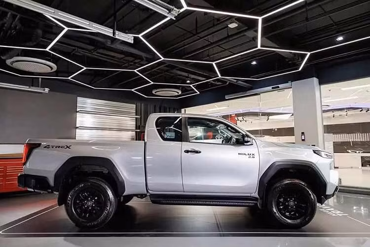 Về ngoại thất, Hilux 2026 thu hút sự chú ý bằng đèn pha LED thanh mảnh, đèn LED định vị ban ngày hình chữ L, lưới tản nhiệt hình chữ nhật cỡ lớn có thể sơn cùng màu thân xe hoặc màu đen, khe gió giả hình tam giác trên cản trước, đèn hậu đảo ngược với đồ họa LED hình chữ C và thùng sau tích hợp cánh gió. Tương tự đối thủ Ford Ranger, xe có thêm bậc bước chân ở hai bên cản sau.