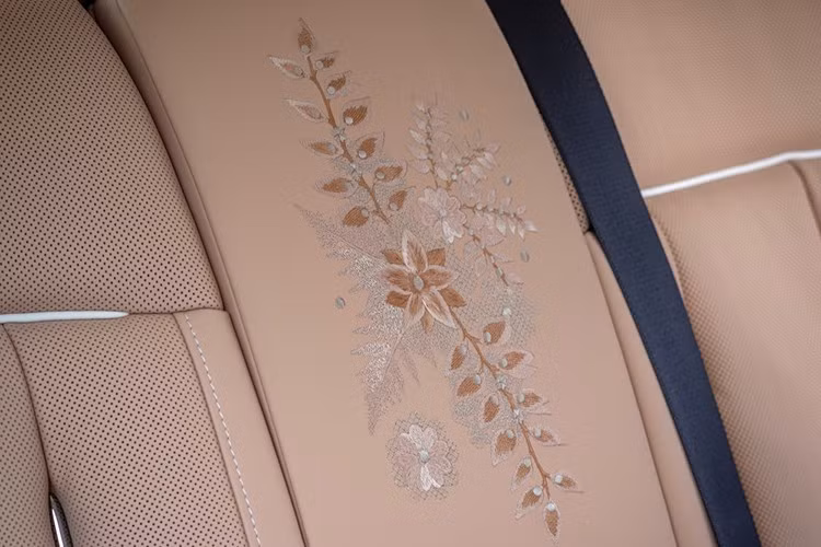 Trên phiên bản độc nhất này, các nhà thiết kế Bespoke đã sáng tạo nên một bức tranh hoa từ vải ren cao cấp, sử dụng đa dạng kỹ thuật thêu, mật độ chỉ và sắc độ màu – Rose Gold, Sunrise và Oatmeal – nhằm tái hiện sống động kết cấu của từng cánh hoa và lá dương xỉ.