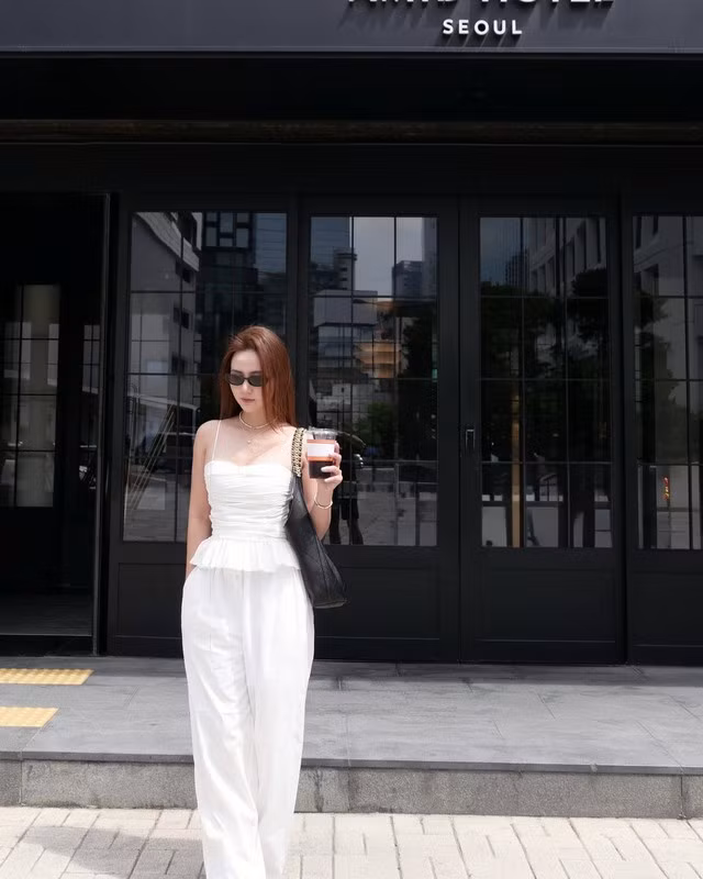 Công thức áo hai dây peplum và quần trắng ống suông tạo nên tổng thể outfit nữ tính cho hot girl Huyền Lizzie. Nhờ tông màu trắng làm chủ đạo, outfit còn mang đến cho người diện sự trẻ trung.