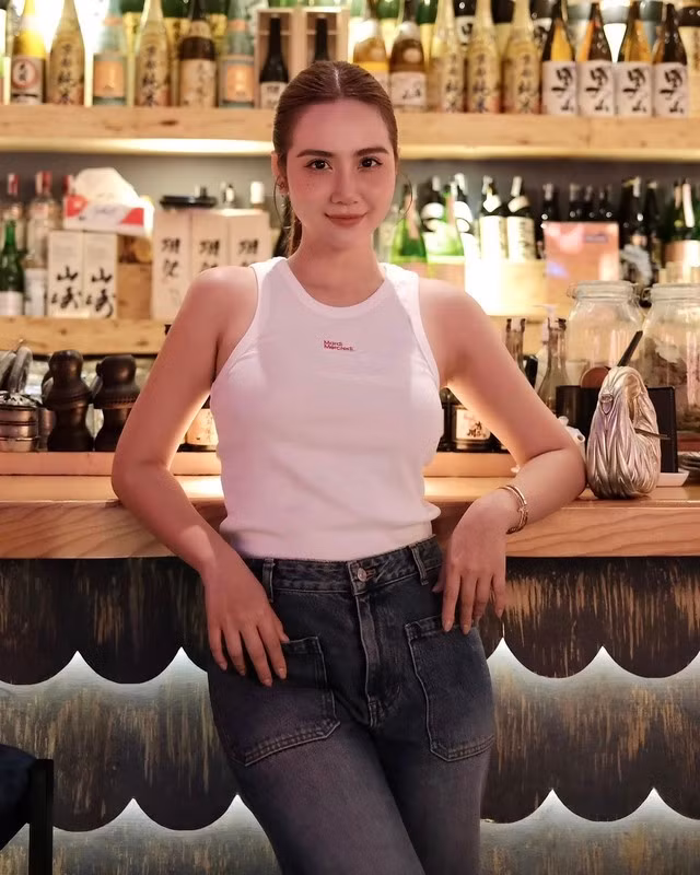 Áo tank top trắng và quần jeans sẫm màu luôn là cặp bài trùng hoàn hảo. Huyền Lizzie đã sơ vin gọn gàng để nâng tầm tổng thể bộ cánh.