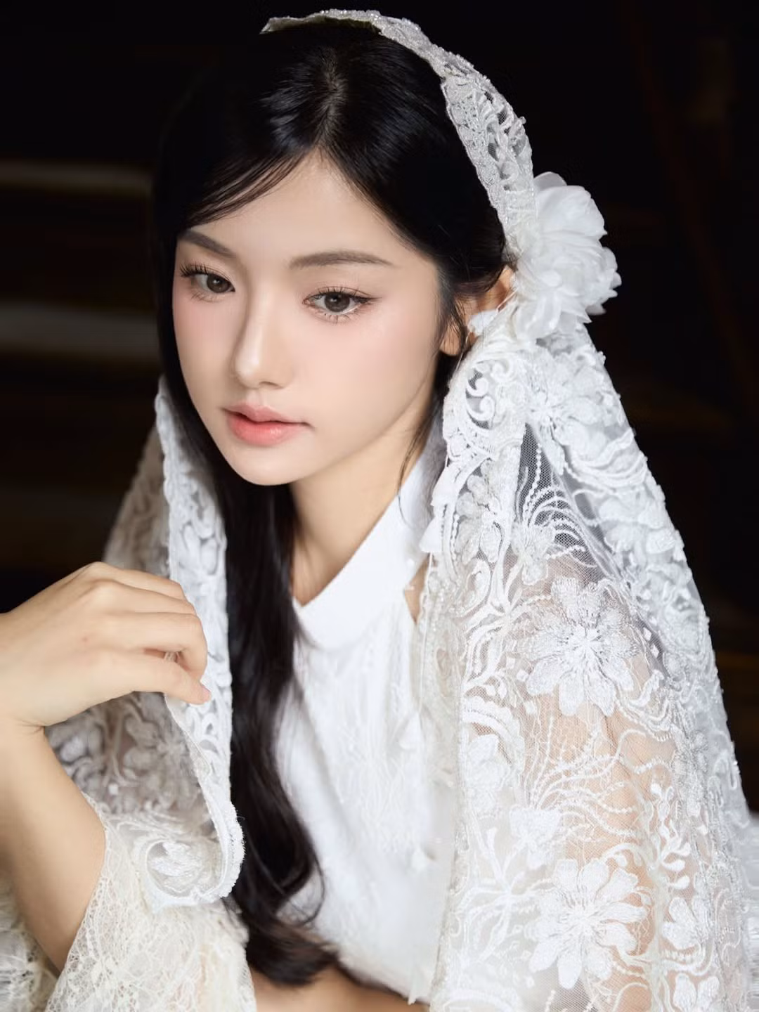 Điểm đặc biệt làm nên “linh hồn” của bộ ảnh chính là chiếc khăn voan ren phủ nhẹ trên mái tóc đen dài. Phụ kiện này gợi liên tưởng đến hình ảnh cô dâu cổ điển hay những thiếu nữ xưa trong tranh lụa, tạo nên vẻ đẹp vừa thuần khiết vừa có chút hoài niệm. Khi Quỳnh Trương khẽ đưa tay giữ mép khăn, từng chuyển động nhỏ cũng trở nên mềm mại, đầy nữ tính.