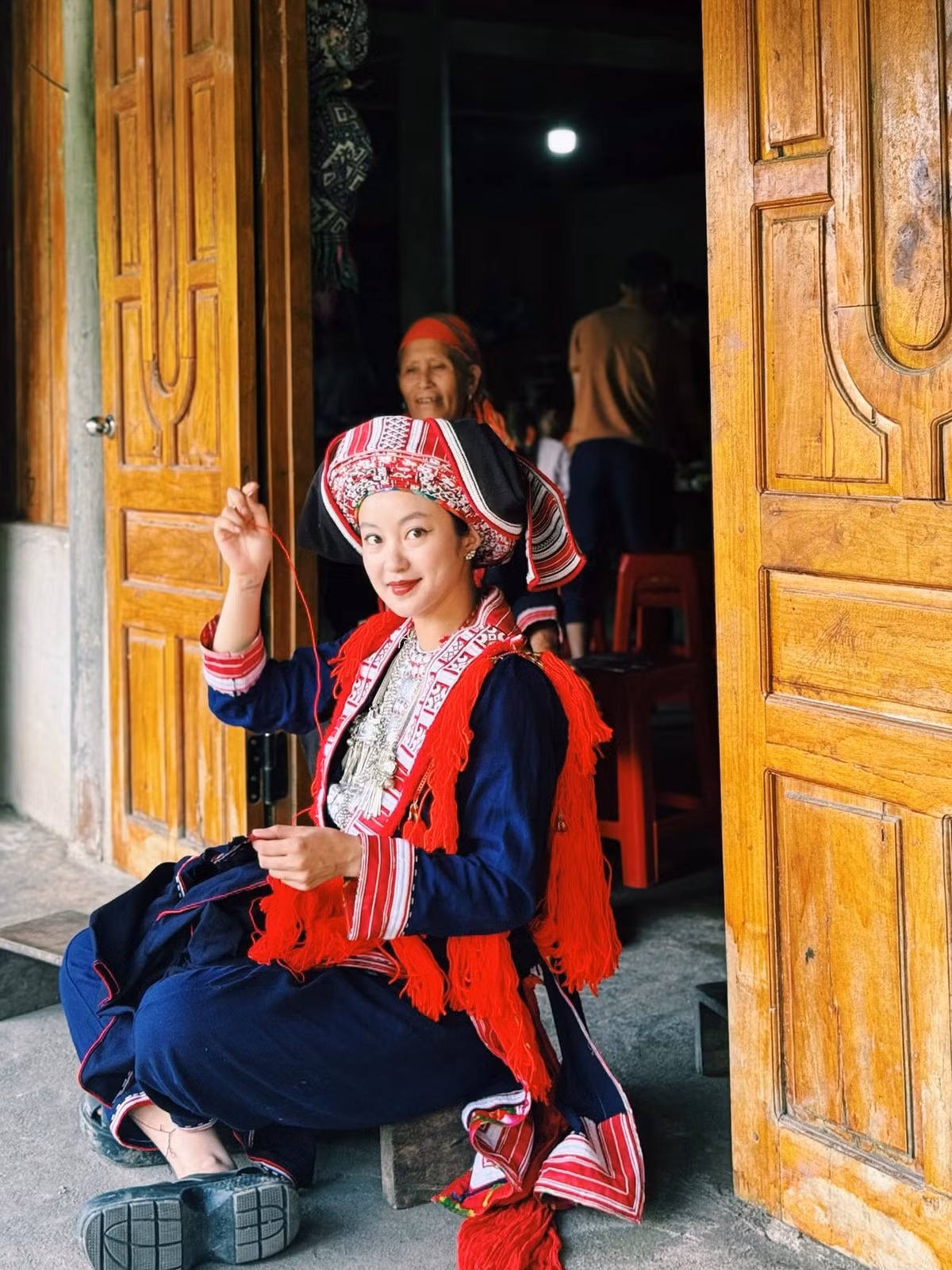 Trang phục truyền thống này thường được thêu tay tỉ mỉ với các họa tiết hoa văn phức tạp, mang ý nghĩa cầu mong hạnh phúc, may mắn. Chiếc khăn đội đầu đỏ nổi bật, những dải tua rua, hay các chi tiết thêu cầu kỳ trên áo và yếm đã góp phần tôn lên vẻ đẹp dịu dàng, nhưng cũng đầy sức sống của cựu hot girl.