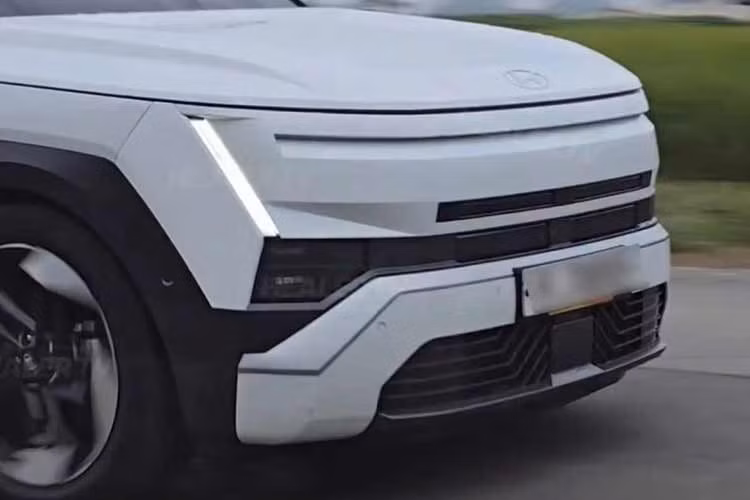 Phần đầu xe Hyundai Tucson 2027 gây chú ý với dải đèn LED chạy ngang kết hợp cụm đèn định vị hình chữ H đặt ở hai bên. Cụm đèn chính được hạ thấp, nằm tách biệt phía dưới, trong khi phần đầu xe dựng đứng hơn trước. Lưới tản nhiệt cũng được thiết kế lại theo hướng kín và gọn hơn.