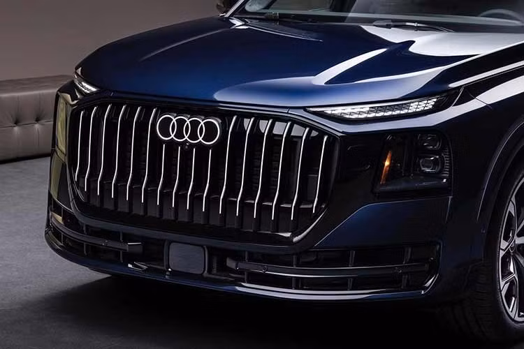Phần đầu xe SUV Audi Q9 mới nổi bật với lưới tản nhiệt cỡ lớn sử dụng các nan dọc cùng thiết kế dựng đứng, kết hợp dải viền màu đen kéo dài sang hai bên tạo diện mạo khỏe khoắn. Phía sau, vị trí gắn biển số được chuyển xuống cản sau, giúp cửa khoang hành lý có thiết kế liền mạch hơn.