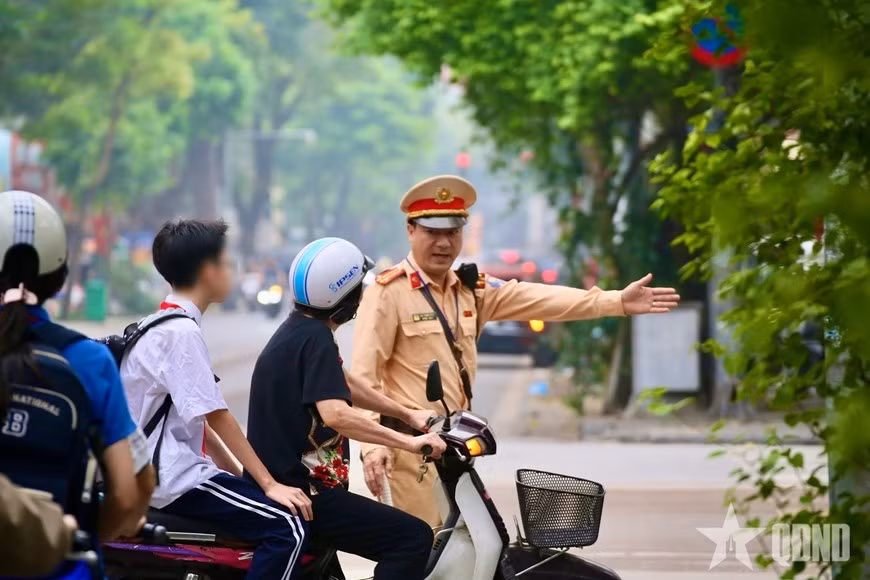 Cảnh sát kiểm tra trường hợp phụ huynh chở học sinh không đội mũ bảo hiểm, sáng 6/4.