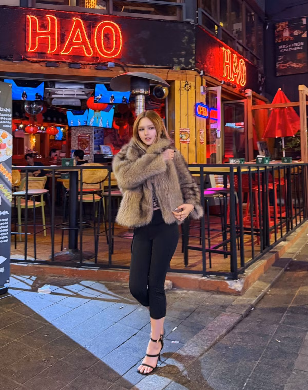 Làn da trắng sáng dưới ánh đèn neon càng làm nổi bật những đường nét thanh tú. Bờ môi đầy đặn với sắc nude quyến rũ tạo điểm nhấn mềm mại nhưng cá tính.