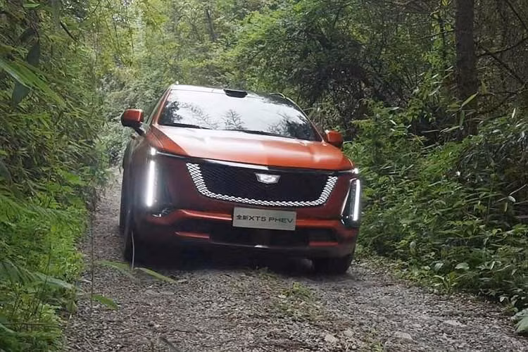 Mẫu xe SUV Cadillac XT5 PHEV 2026 mới ra mắt mang ngôn ngữ thiết kế đồng điệu với các dòng xe thuần điện mới nhất của hãng như Optiq, Lyriq và Vistiq. Phần đầu xe nổi bật với lưới tản nhiệt dạng khiên đen bóng tích hợp dải đèn viền chiếu sáng, kết hợp cùng cụm đèn pha đặt dọc đặc trưng.