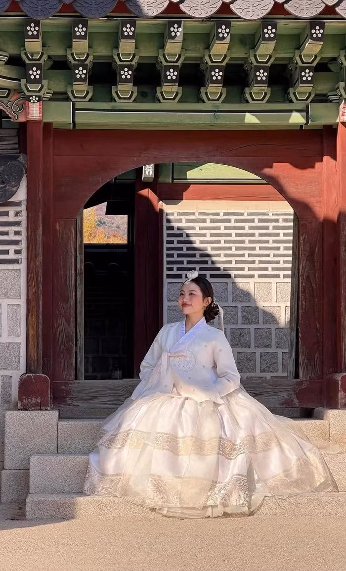 Cô chọn một bộ Hanbok truyền thống mang tông màu trắng kem tinh khôi, vô cùng thanh lịch. Thiết kế có nhiều lớp vải voan mỏng, bồng bềnh, cùng các chi tiết hoa văn thêu chìm tinh xảo trên thân váy và áo