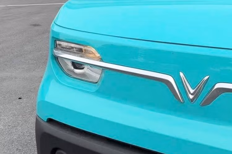 Phần đầu xe nổi bật với thanh crôm tạo hình cánh chim ôm quanh logo “V”, vốn là nét nhận diện chung của nhiều mẫu VinFast. Hệ thống đèn phía trước vẫn sử dụng bóng halogen, trong khi gương chiếu hậu chỉnh cơ dạng cầu tương tự trên mẫu xe mini điện VF3.