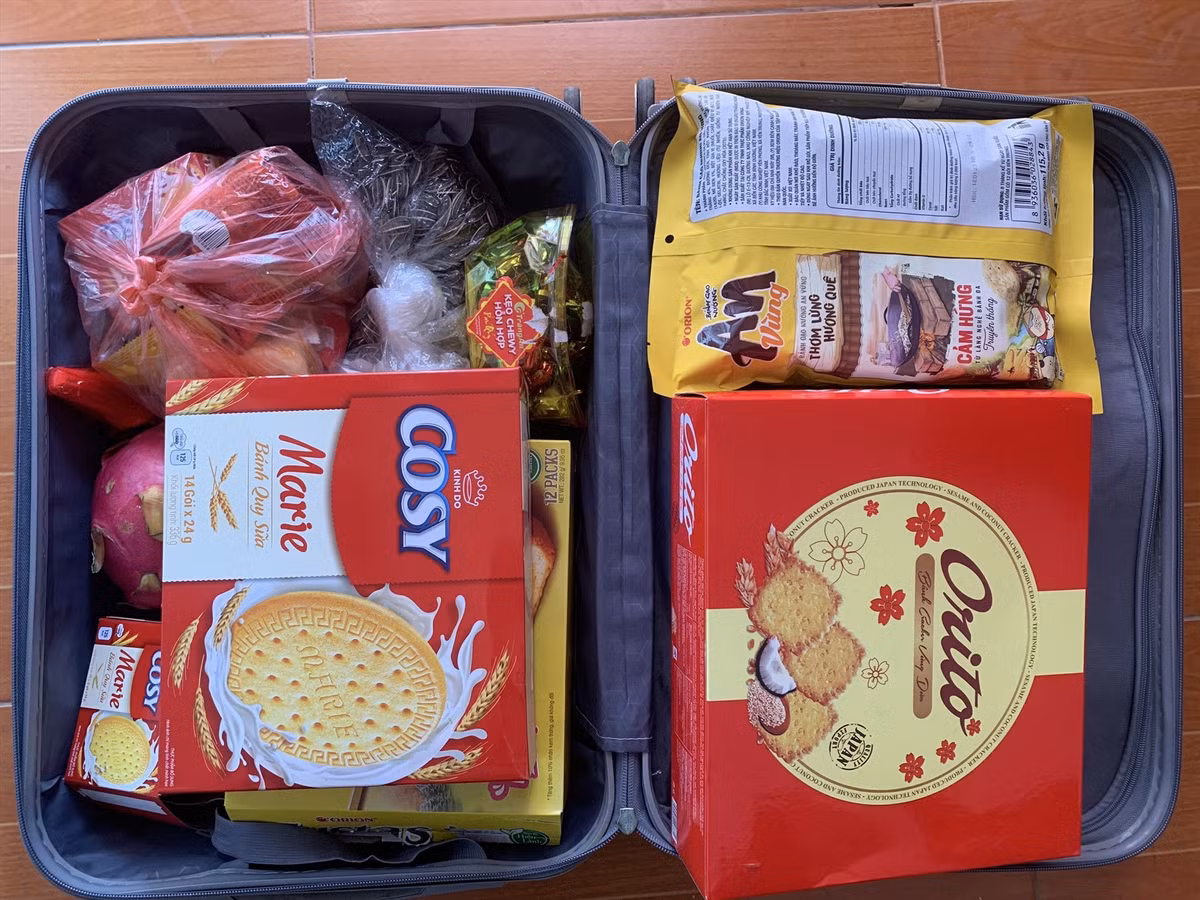 Danh sách đồ quê được mang theo vô cùng phong phú. Phổ biến nhất vẫn là bánh chưng, bánh tét còn nguyên hương vị Tết, kèm giò lụa, chả quế, thịt kho, nem rán cấp đông sẵn. Ngoài ra còn có trứng gà ta, mớ rau xanh bố mẹ vừa hái ngoài vườn, cá khô, mực khô, ruốc, lạc rang, dưa muối… Mỗi món được gói ghém cẩn thận, chia thành từng túi nhỏ, ghi chú rõ ràng để con dễ bảo quản và sử dụng.