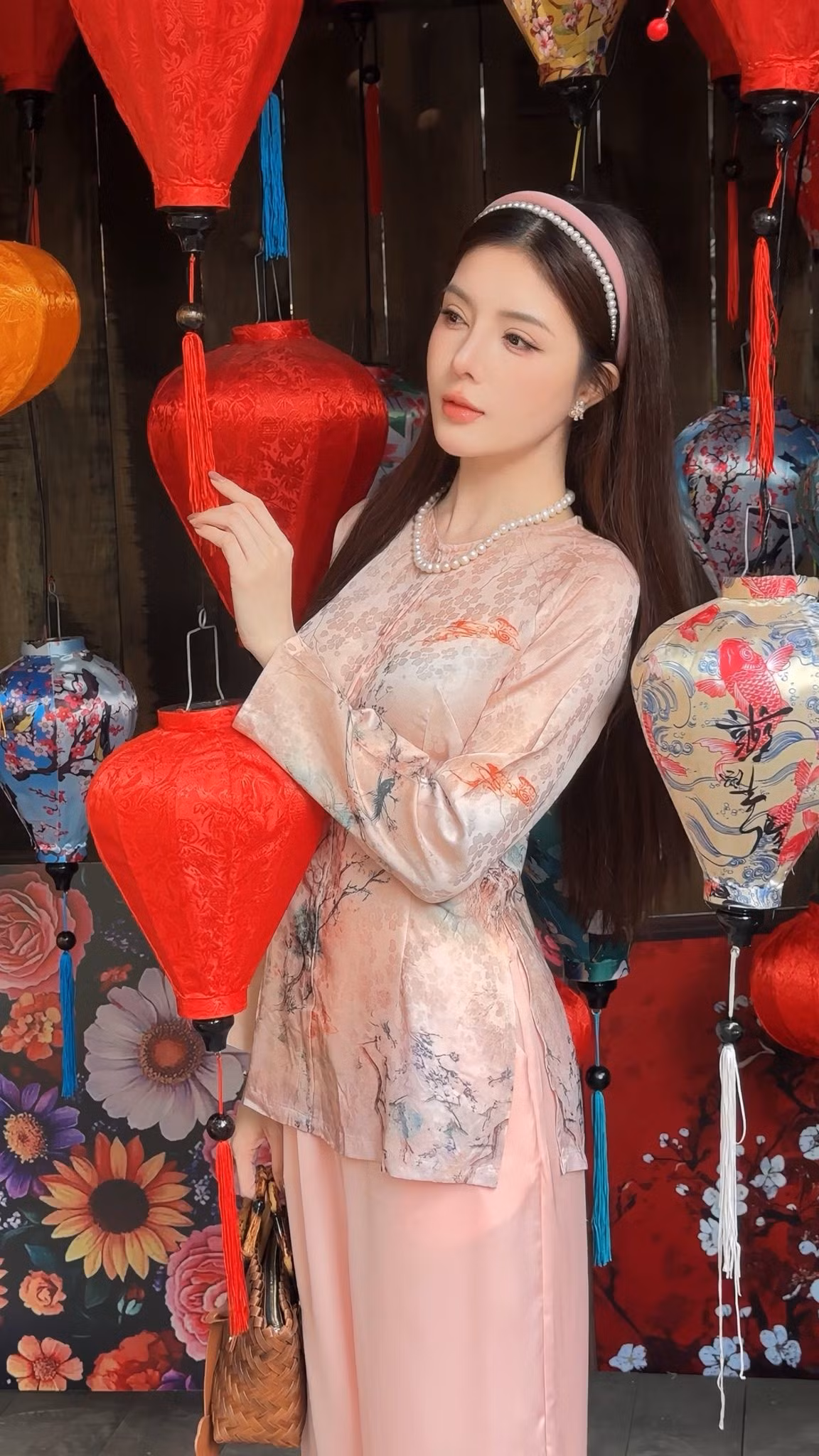 Điểm cộng lớn trong loạt ảnh chính là cách người đẹp phối phụ kiện. Băng đô đính ngọc trai, vòng cổ và hoa tai đồng điệu mang lại cảm giác sang trọng, nữ tính mà không hề rườm rà. Chiếc quạt tay tre mộc mạc khi được Lilly Luta cầm trên tay lại trở thành đạo cụ “đắt giá”, góp phần hoàn thiện hình ảnh một cô gái Á Đông dịu dàng, e ấp.