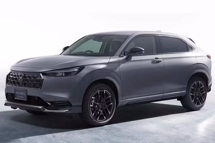 Điểm thay đổi dễ nhận biết trên tất cả các phiên bản Honda Vezel 2027 là phần chóa đèn chiếu sáng phía trước được làm tối màu, mang lại vẻ ngoài cá tính hơn. Ở các biến thể cao cấp như e:HEV Z và gói Play Package, toàn bộ phần ốp nhựa bảo vệ quanh hốc bánh và cản xe trước/sau chuyển sang sơn cùng màu thân xe thay vì để nhựa đen nguyên bản.