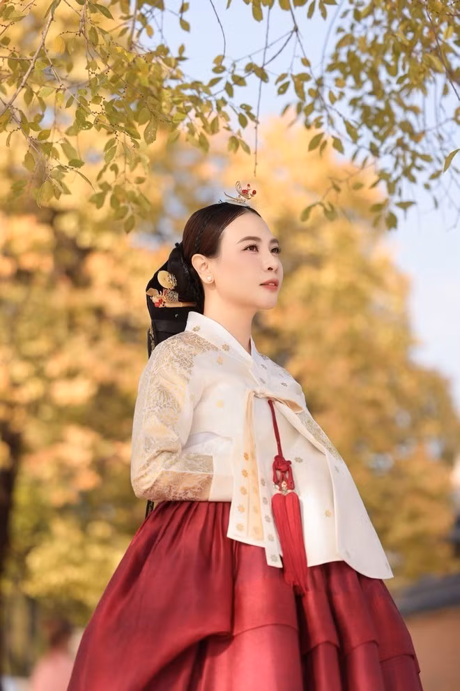 Tóc búi cao kiểu truyền thống, cài trâm hoa nhỏ xinh, Đàm Thu Trang với makeup look tông màu cam hồng nhẹ nhàng với - tất cả tạo nên hình ảnh như một hoàng hậu bước ra từ phim cung đấu.