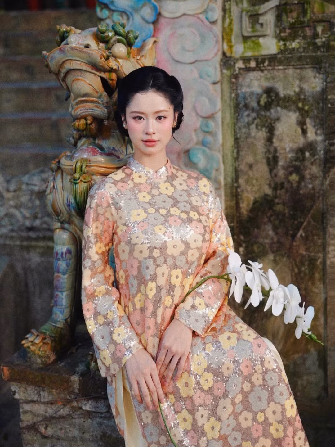 Trong những khung hình được chia sẻ, Hàn Hằng lựa chọn áo dài dáng suông, họa tiết hoa nhã nhặn trên nền chất liệu ánh nhẹ, tôn lên vẻ thanh thoát và nữ tính.