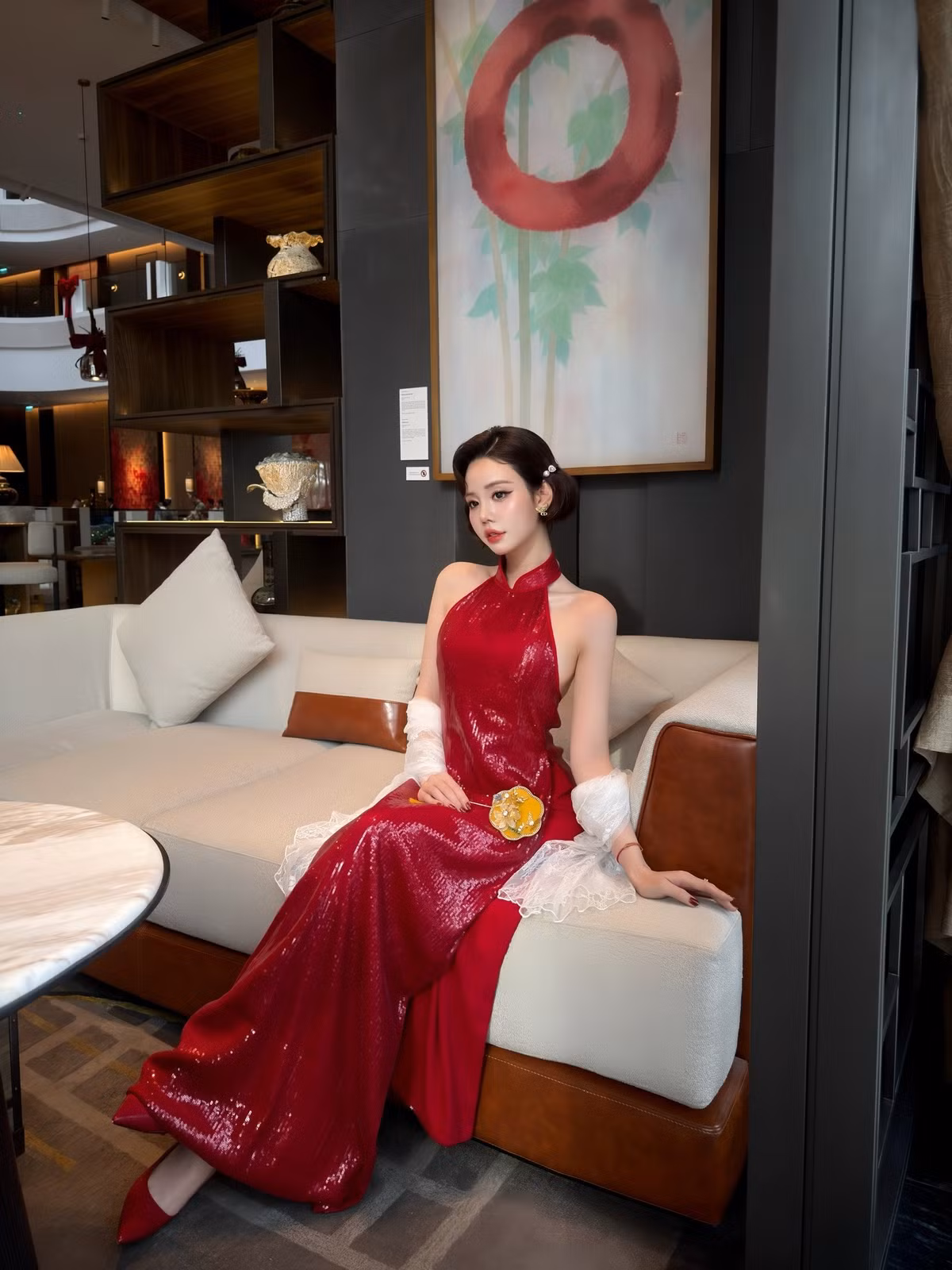 Kiểu tóc uốn gợn nhẹ, tạo hình cổ điển kết hợp cùng lối trang điểm tinh tế càng làm nổi bật đôi mắt to tròn, sống mũi cao và thần thái đài các. Áo dài cách tân với phần cổ yếm, lưng trần khéo léo khoe bờ vai mảnh mai, mang đến cảm giác vừa kín đáo vừa gợi cảm.