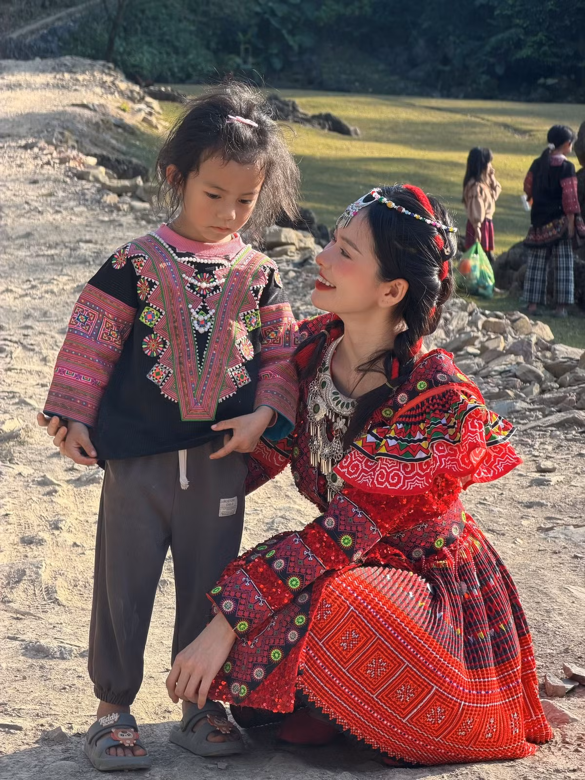 Giữa không gian núi đá, rừng xanh và ánh nắng dịu nhẹ đầu năm, Đỗ Yên Đan xuất hiện với thần thái rạng rỡ, gương mặt trang điểm nhẹ nhàng nhưng nổi bật. Kiểu tóc tết gọn gàng, phụ kiện cài đầu truyền thống càng làm tôn lên vẻ đẹp thuần khiết, trong veo của cô nàng.