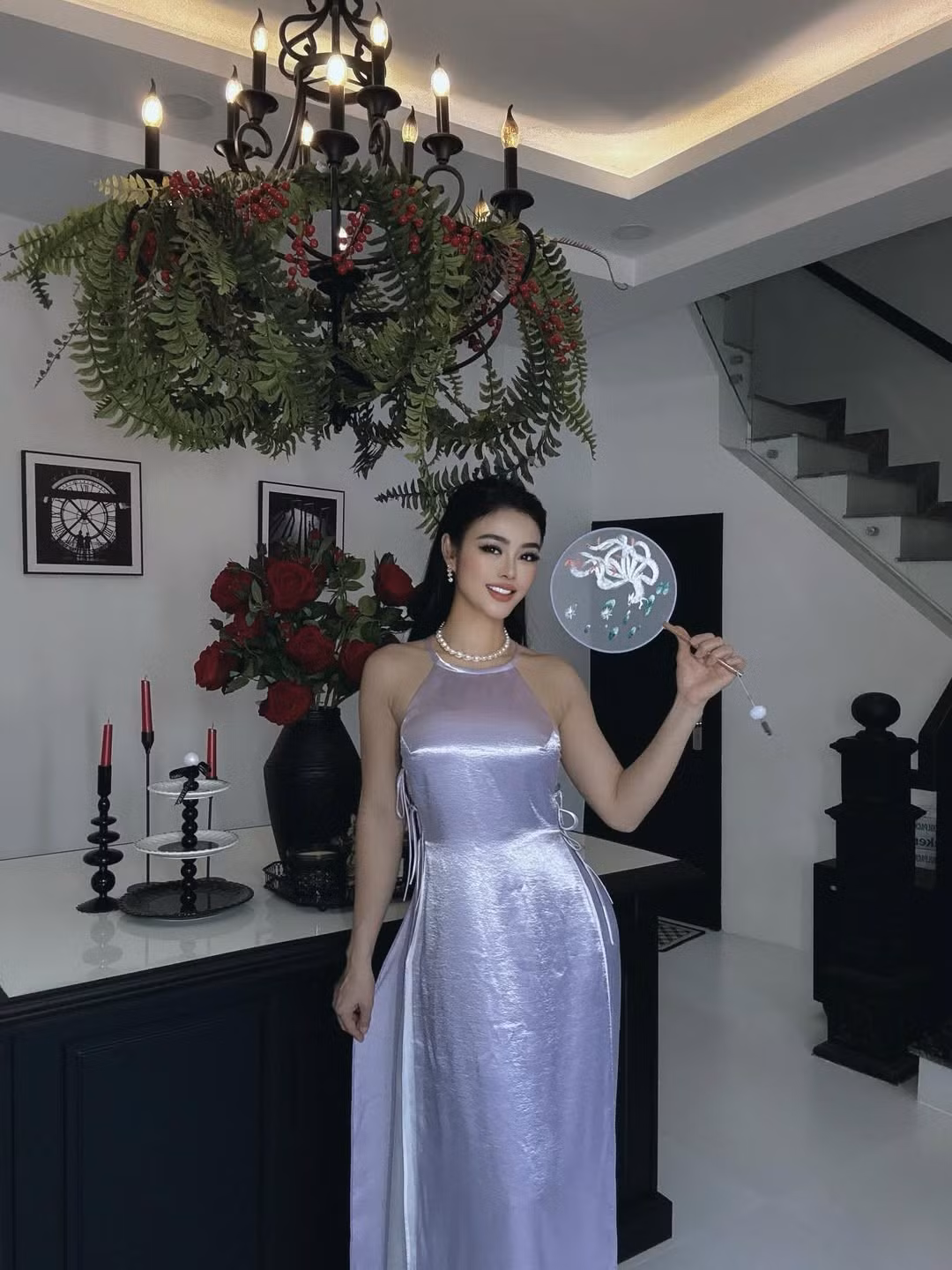 Trong loạt hình mới, Julia Hồ lựa chọn thiết kế áo dài cách tân với chất liệu ánh satin bắt sáng, phom dáng ôm nhẹ tôn lên vóc dáng gợi cảm. Gam màu tím bạc giúp tổng thể vừa mềm mại vừa hiện đại, kết hợp cùng chuỗi ngọc trai và lối trang điểm sắc sảo càng làm nổi bật thần thái sang trọng của người đẹp sinh năm 1990. Mái tóc dài suôn mượt, nụ cười rạng rỡ và cách tạo dáng nhẹ nhàng giúp cô ghi điểm với hình ảnh nữ tính nhưng không kém phần quyến rũ.