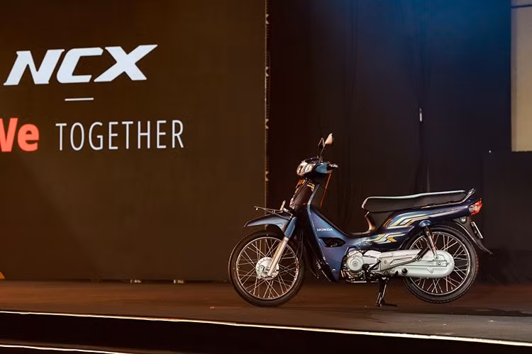 Mẫu xe máy số phổ thông Honda Dream NCX 125i 2026 mang kiểu dáng underbone quen thuộc, được nhấn nhá bởi dải tem Hyper Dynamic Stripe cùng các chi tiết mạ vàng, kim cương nhân tạo và logo NCX nổi bật.