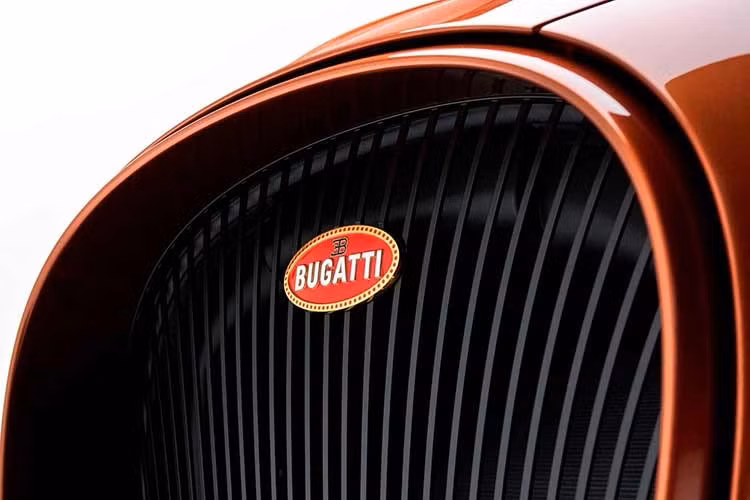 Khu vực đầu xe Bugatti W16 Mistral Le Retour du Jeune Prince vẫn duy trì lưới tản nhiệt hình móng ngựa truyền thống của thương hiệu nhưng các nan bên trong được định hình theo dạng dọc, kết hợp cùng logo macaron Bugatti mạ vàng sang trọng.