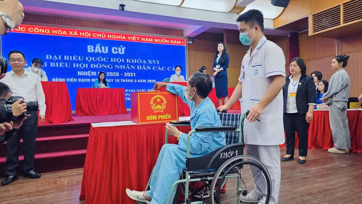 Không chỉ tại các khu dân cư, không khí bầu cử còn lan tỏa tới nhiều nơi đặc biệt. Tại Bệnh viện Bạch Mai (Hà Nội), nhiều bệnh nhân đang điều trị cũng được tạo điều kiện tham gia bỏ phiếu. Anh Nguyễn Văn Tuyên (SN 1983, quê Mai Sơn, Sơn La), đang điều trị bệnh xương khớp, được các điều dưỡng hỗ trợ đẩy xe lăn tới điểm bỏ phiếu. Dù đang nằm viện, anh vẫn xúc động khi được thực hiện quyền công dân của mình trong không khí trang nghiêm và ấm áp. Ảnh Hanoimoi