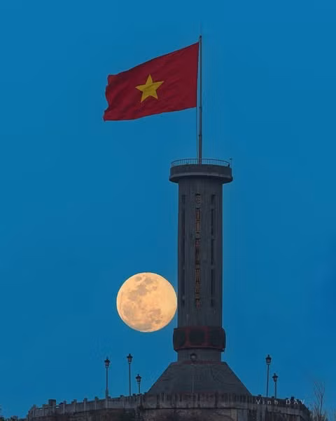 Một trong những khoảnh khắc ấn tượng nhất mà du khách có thể trải nghiệm khi đến Lũng Cú là cảnh Mặt Trăng dần dần hiện lên đúng trên đỉnh cột cờ, ngay lúc cờ đỏ sao vàng phấp phới trong làn gió mạnh. Ảnh Vinh Dav