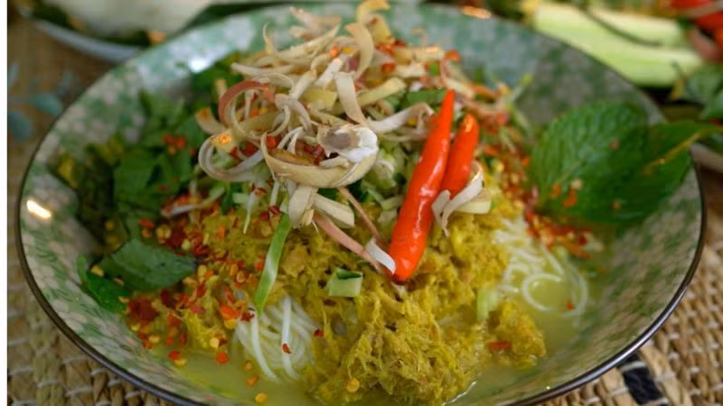 Cùng là món ăn sáng, num banh chok lại mang đến cảm giác nhẹ nhàng hơn với bún gạo lên men chan cà ri cá xanh, ăn kèm rau sống và các loại thảo mộc như bạc hà, húng quế, ngò rí và lá laksa. Tô bún thanh mát, thoang thoảng mùi thảo mộc được xem là “linh hồn” của bữa sáng Campuchia. Ảnh Internet
