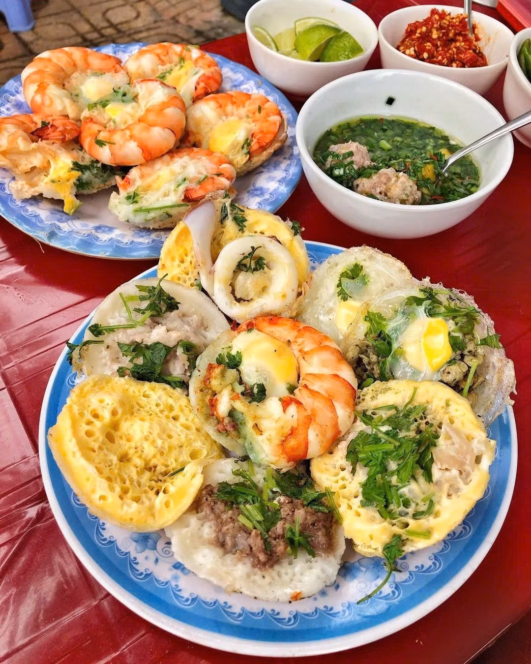 Bánh căn Nha Trang được đúc trong khuôn đất, nhân tôm, mực, trứng cút hoặc thịt băm. Khi bánh chín, người bán nhanh tay gắp ra đĩa, ăn kèm mỡ hành, xoài xanh bào sợi và chén nước chấm pha từ mắm nêm, nước cá hoặc nước mắm tỏi ớt. Quán bánh căn Tháp Bà, hẻm Nguyễn Trãi hay đường Tô Hiến Thành đều rất nổi tiếng, giá chỉ từ 20.000 – 30.000 đồng/phần. Ảnh MIA