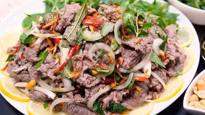 Sau khi trộn chanh, thịt bò thường được đảo cùng tỏi phi, hành phi để tăng mùi thơm. Khi bày ra đĩa, bò tái chanh được đặt trên lớp rau sống, rắc thêm ớt thái lát, lạc rang giã dập, mang đến sự hài hòa giữa vị chua, cay, béo và bùi. Taste Atlas gợi ý bò tái chanh phù hợp dùng như món khai vị, ăn kèm nước chấm và các loại đồ uống có cồn. Ảnh minh họa