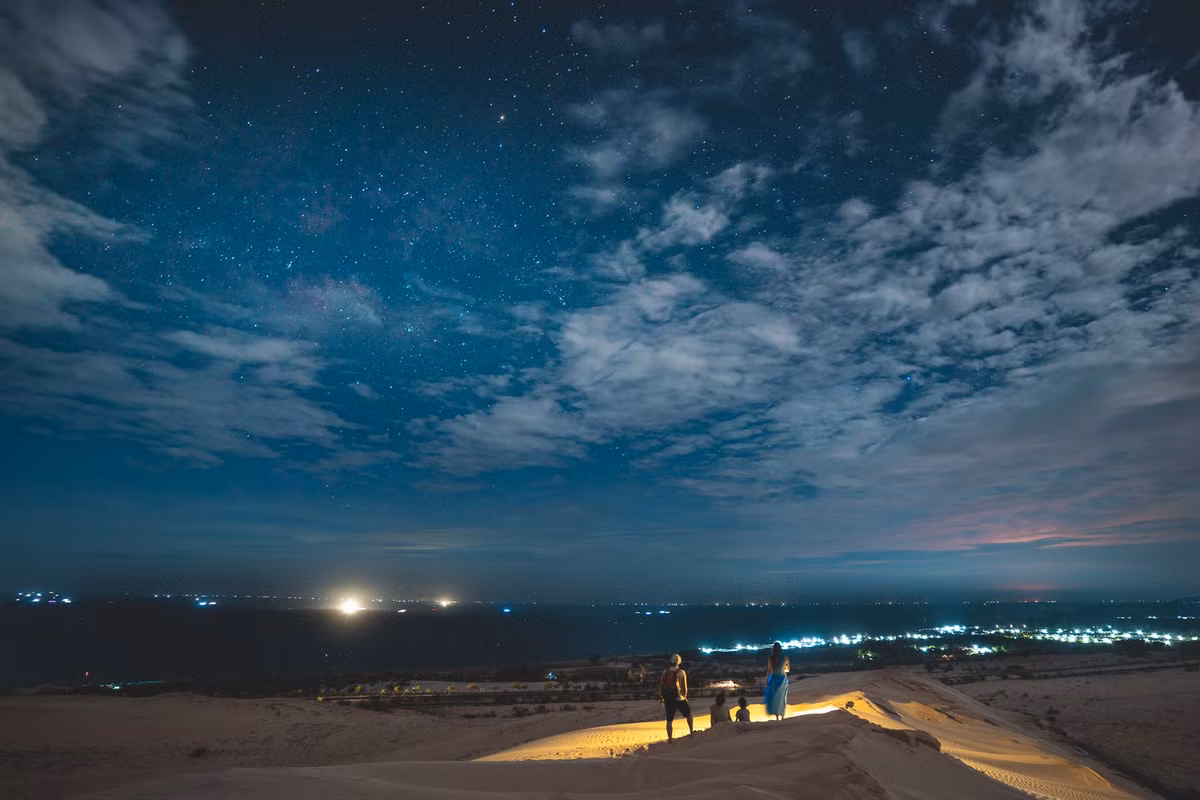 Nếu ban ngày, đồi cát Mũi Né (TP Phan Thiết, Bình Thuận) hấp dẫn bởi sắc vàng rực rỡ, từng con dốc mượt như lụa thu hút du khách trượt cát, thì về đêm, nơi này lặng lẽ đến lạ. Khi ánh nắng tắt dần sau lưng núi, cả không gian rộng lớn chìm vào màn tối, nhường chỗ cho ánh trăng vắt ngang bầu trời và gió nhẹ thổi lướt qua những rặng phi lao. Ảnh Nguyễn Hồng Nhật