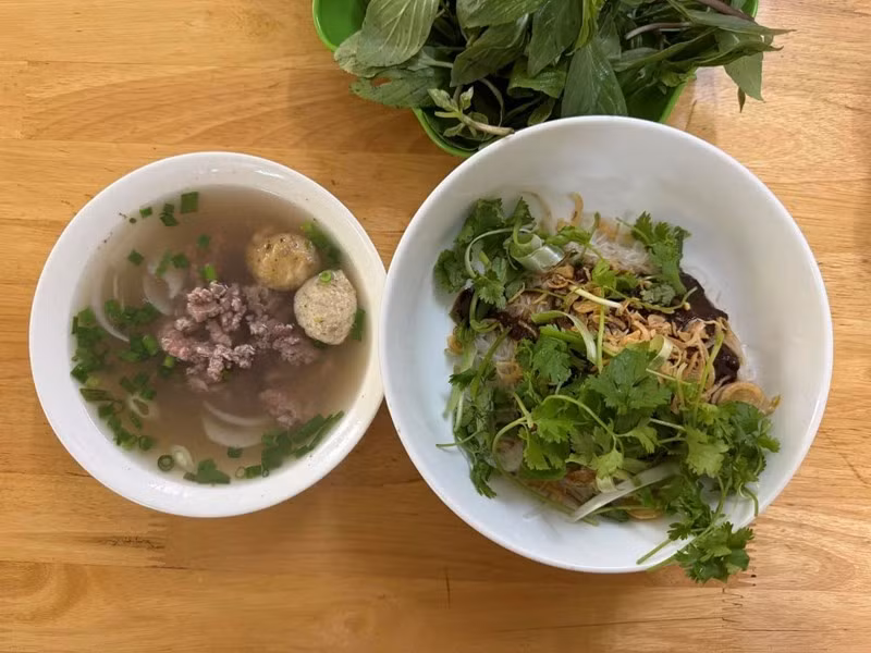 Song hành với tô phở khô là tô nước lèo trong veo, được ninh kỹ từ xương, mang vị ngọt thanh tự nhiên. Trong nước dùng thường có xương hầm, bò viên, thịt bò hoặc thịt gà, tùy theo bí quyết của từng quán. Ảnh nguồn Internet