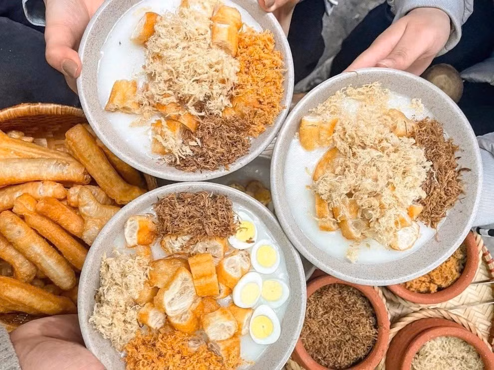 Sáng sớm, Hà Nội lại níu chân người ta bằng cháo sườn quẩy. Gánh cháo Hàng Bồ, đã hơn ba mươi năm, vẫn đều đặn nghi ngút khói mỗi khi trời trở gió. Bát cháo xay mịn, ruốc thơm, quẩy giòn – thứ giản dị mà đủ khiến buổi sáng lạnh trở nên ấm lòng. Ảnh Ngọc Linh
