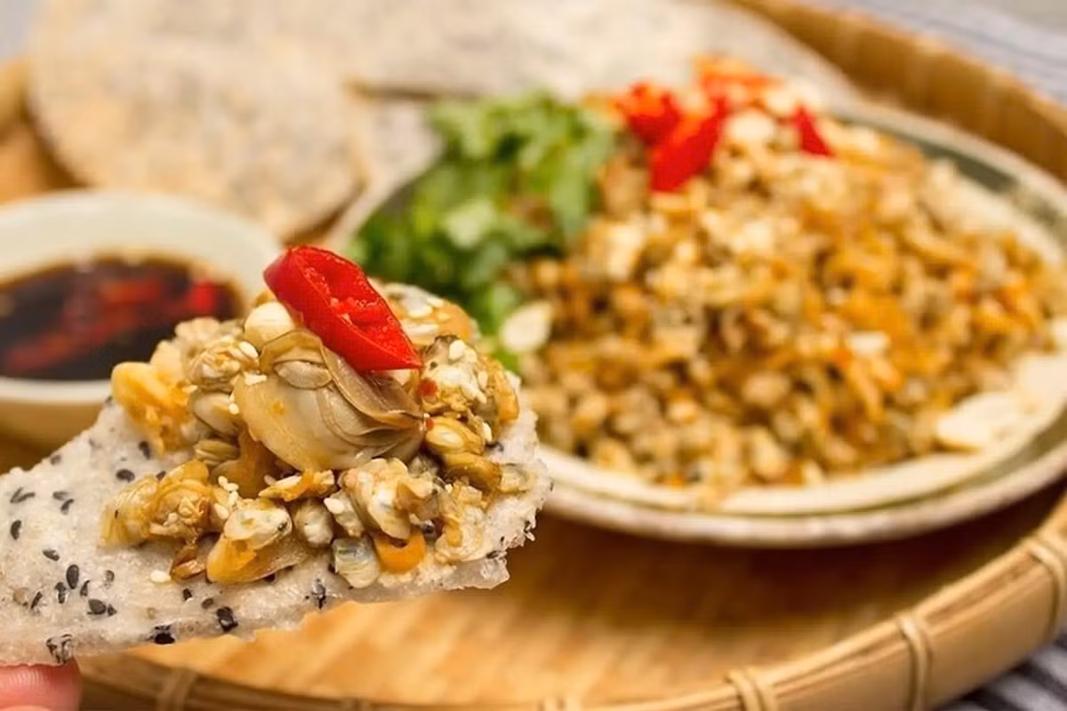Là món ăn đặc trưng của xứ Nghệ, bánh đa xúc hến gây thương nhớ bởi sự hòa quyện tinh tế giữa vị ngọt mát của hến sông Lam và độ giòn thơm đặc trưng của bánh đa Đô Lương. Hến được đánh bắt tươi, qua công đoạn tách vỏ tỉ mỉ, sau đó xào cùng hành, mỡ và gia vị đến khi dậy mùi hấp dẫn. Khi thưởng thức, người ta dùng bánh đa xúc trực tiếp phần hến xào nóng hổi – một sự kết hợp dân dã nhưng đầy mê hoặc. Vị béo, giòn, mặn mà lan tỏa nơi đầu lưỡi khiến bất cứ ai một lần nếm thử cũng khó lòng quên được. Ảnh FPT